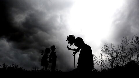Eine Silhouette einer Hexe mit zwei Kindern in der Nacht