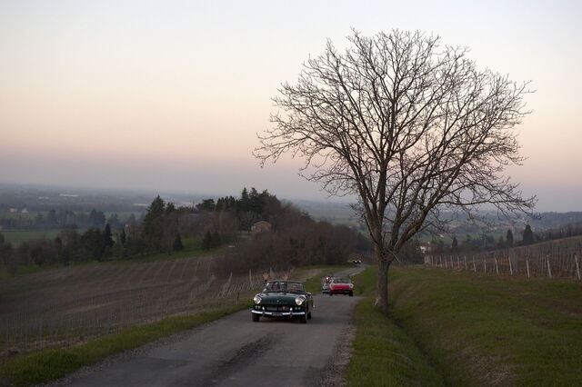 Auto auf einer toskanischen Straße bei Sonnenuntergang